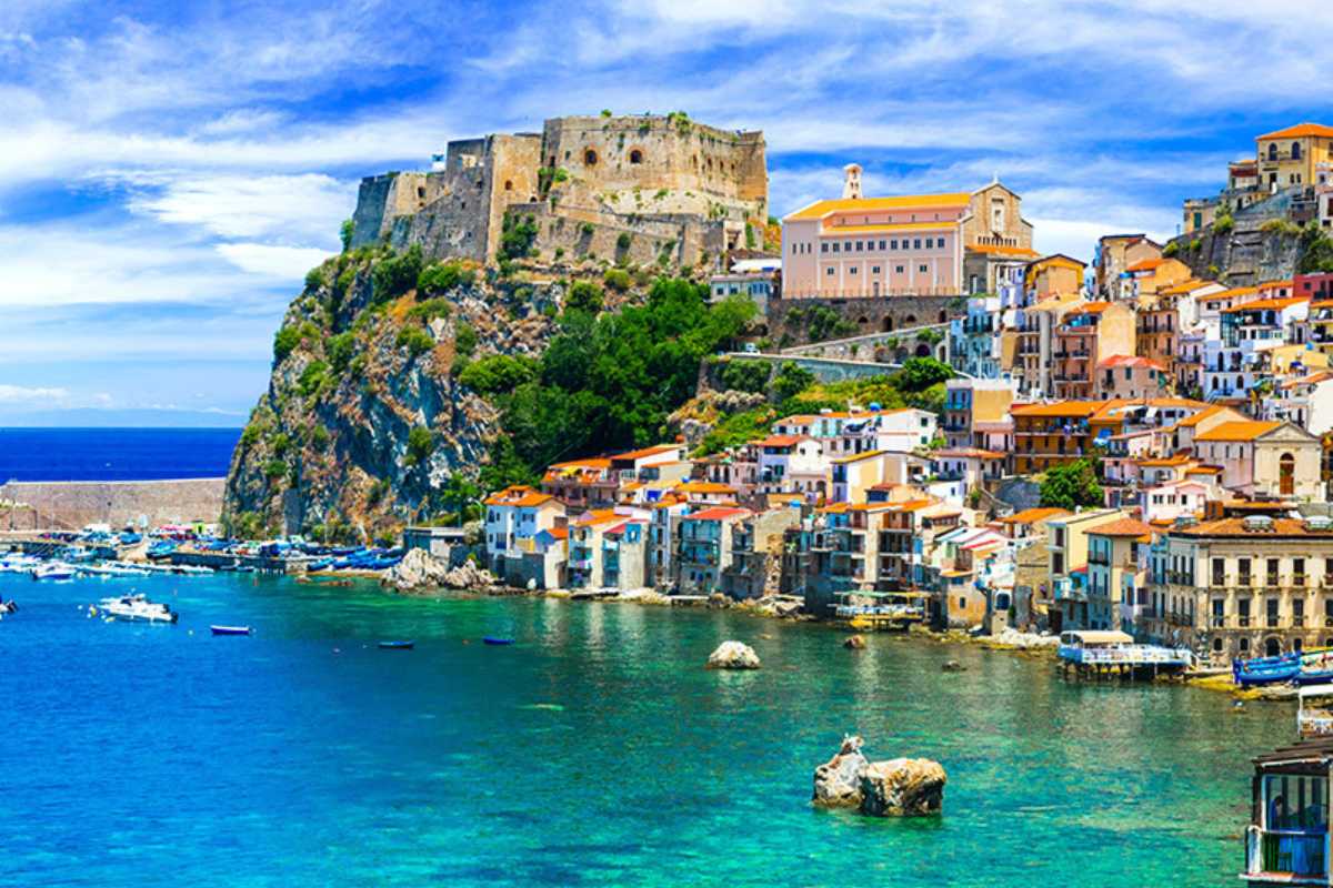Barca in navigazione davanti alla costa di Capovaticano, acqua cristallina, scogli bianchi e faro sullo sfondo, atmosfera estiva e rilassata