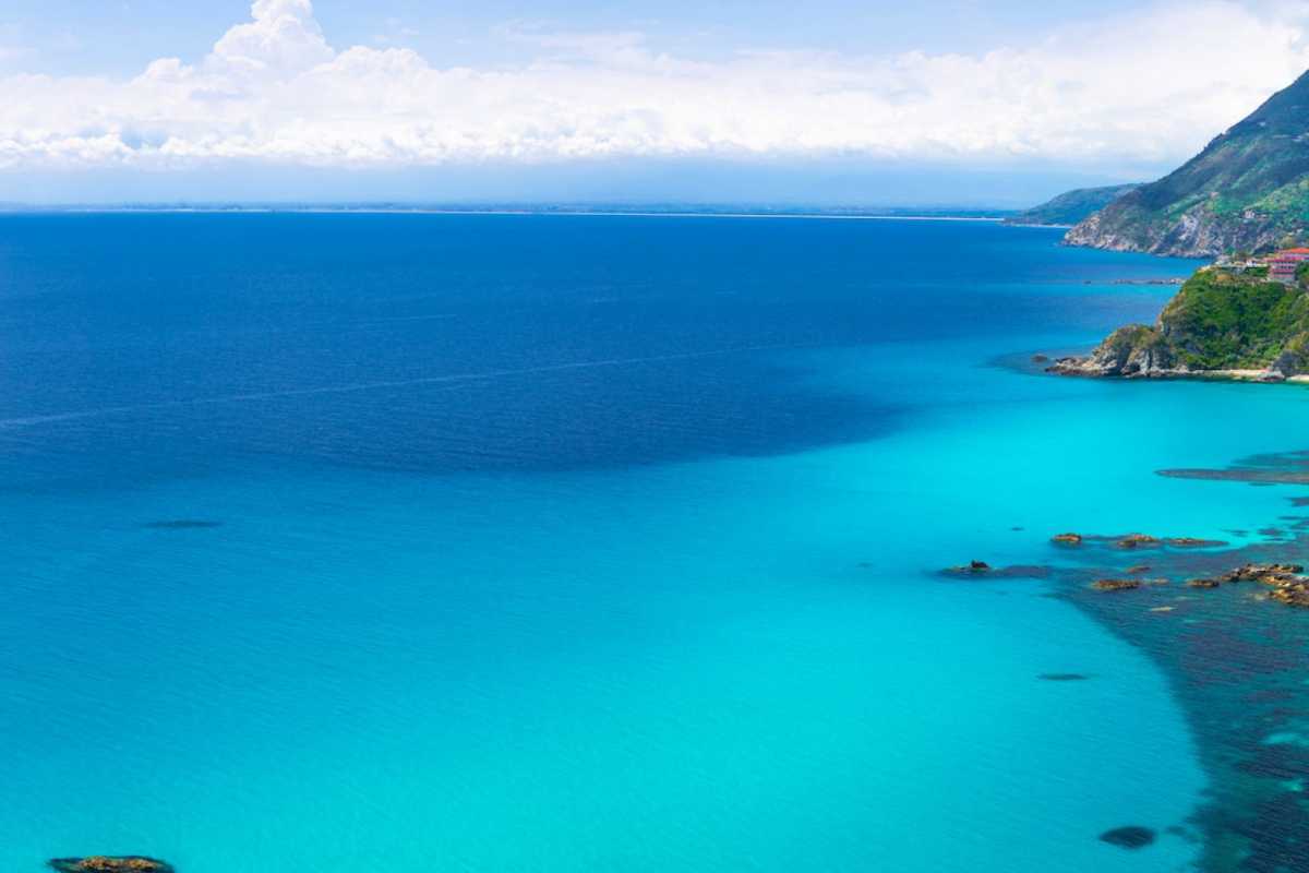 Coppia che brinda in barca al tramonto davanti a Capovaticano, colori caldi, Stromboli all'orizzonte, atmosfera intima e romantica